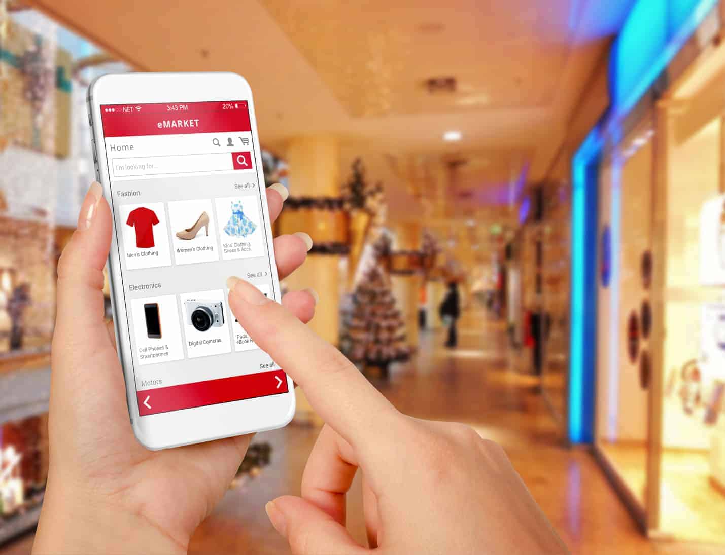 Web design from EWD (Esthetig Web Design) web design page - eCommerce Online Shops. Photo of female hands holding a mobile phone and buying from an online shop whilst in a shopping centre decorated for Christmas.